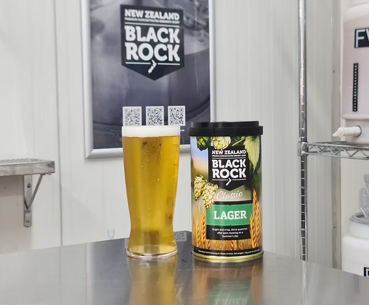 Glass of beer and can of Black Rock Lager on a counter with a branded backdrop.