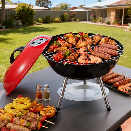 Small barbecue grill with skewered food on a table outdoors
