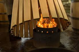 Wooden fire pit with flames inside, surrounded by wooden slats.