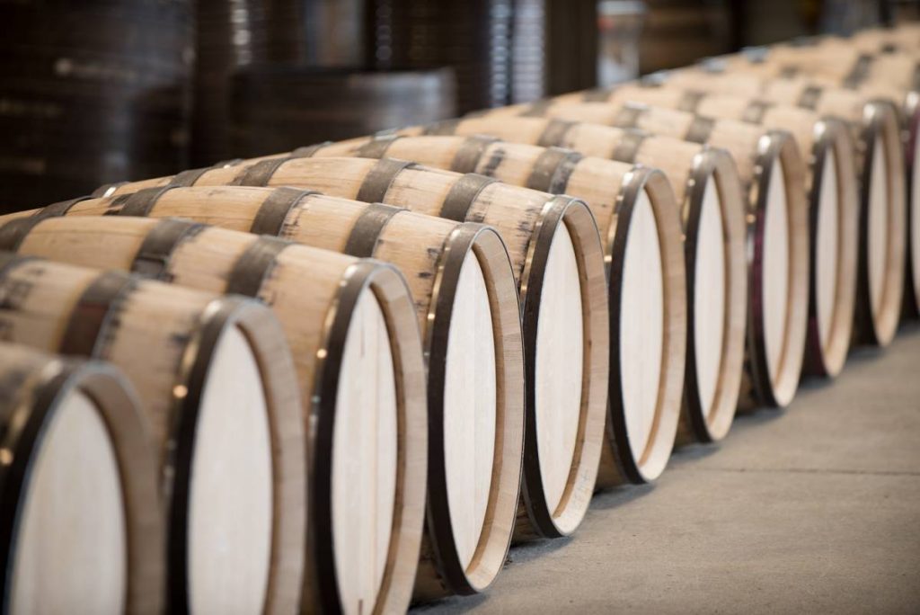 Row of wooden barrels with white ends on a wooden floor
